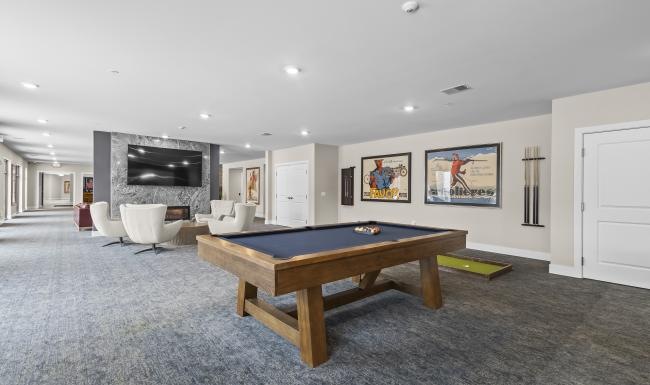 a large living room with a pool table and chairs